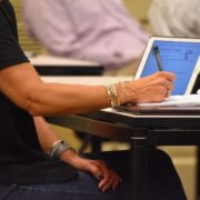 woman taking notes at a business conference while working on a laptop